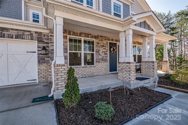 property entrance featuring stone siding, a porch, and a garage