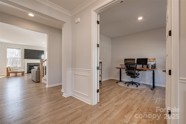 office space with a glass covered fireplace, light wood-style flooring, recessed lighting, and ornamental molding