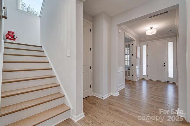 entryway with visible vents, baseboards, stairway, ornamental molding, and light wood-style flooring