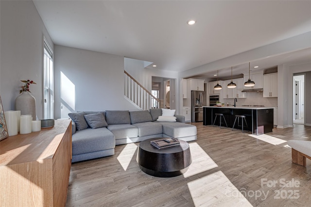 living area with recessed lighting, baseboards, stairs, and light wood-style floors