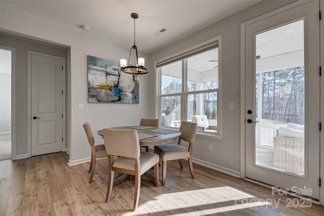 dining room with light wood finished floors, visible vents, baseboards, and an inviting chandelier