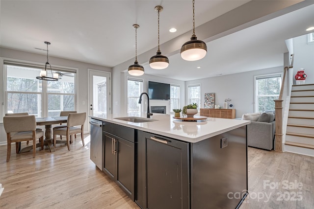 kitchen featuring light wood finished floors, open floor plan, light countertops, a wealth of natural light, and a sink