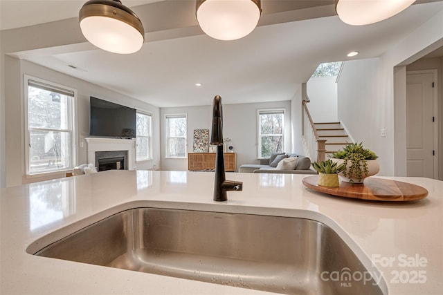 kitchen with a wealth of natural light, open floor plan, a fireplace, and a sink