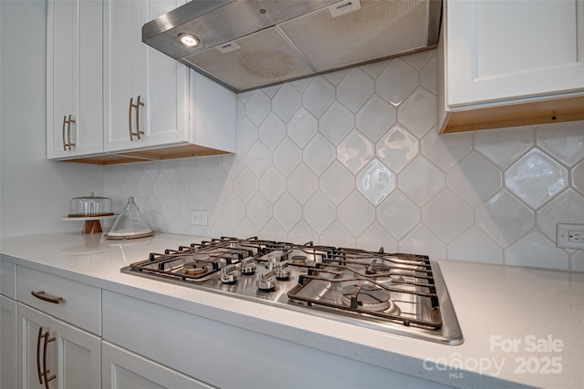 kitchen featuring under cabinet range hood, white cabinets, light countertops, and stainless steel gas stovetop