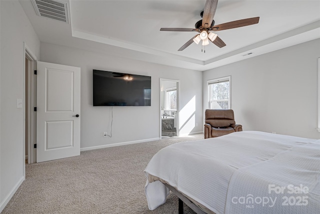 carpeted bedroom featuring a tray ceiling, baseboards, visible vents, and ceiling fan