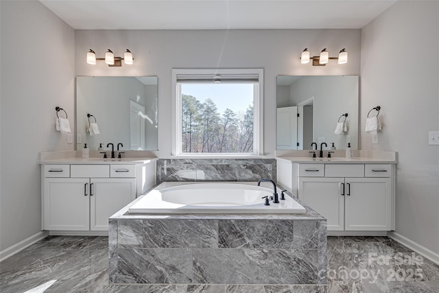 bathroom with a bath, marble finish floor, two vanities, and a sink