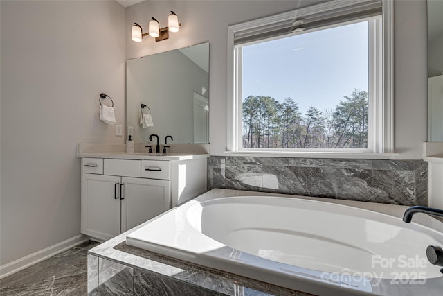 bathroom featuring vanity, a garden tub, baseboards, and marble finish floor