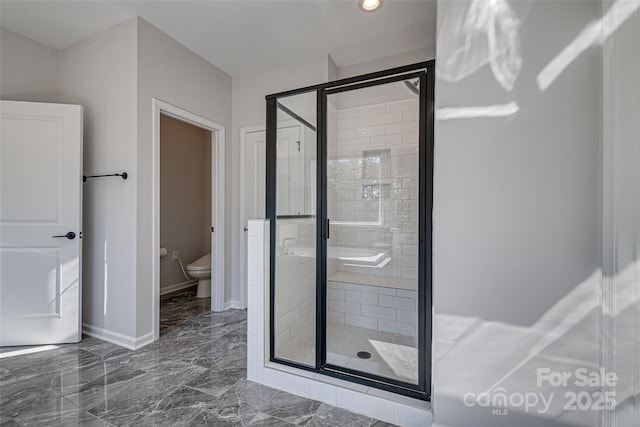 bathroom featuring marble finish floor, a stall shower, toilet, and baseboards