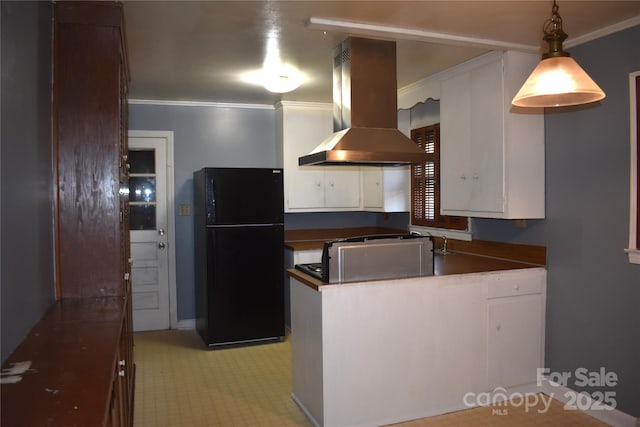 kitchen with dark countertops, a peninsula, island exhaust hood, freestanding refrigerator, and white cabinetry