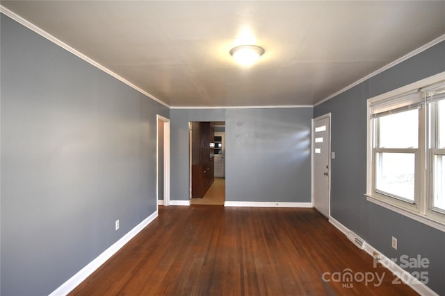 spare room with crown molding, wood finished floors, and baseboards