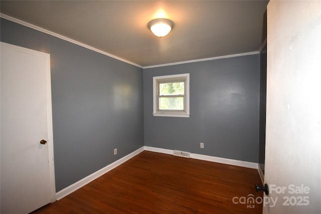 empty room featuring visible vents, baseboards, wood finished floors, and crown molding