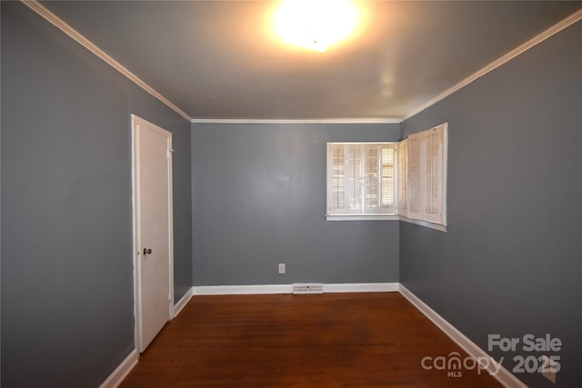 empty room featuring wood finished floors, baseboards, and ornamental molding