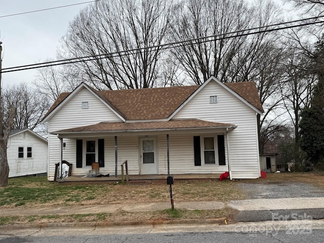 view of front facade featuring roof with shingles and covered porch