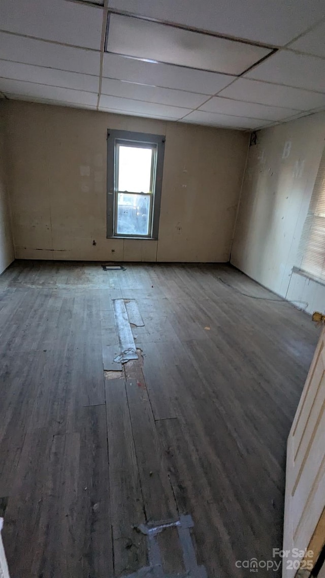 unfurnished room with wood finished floors and a paneled ceiling