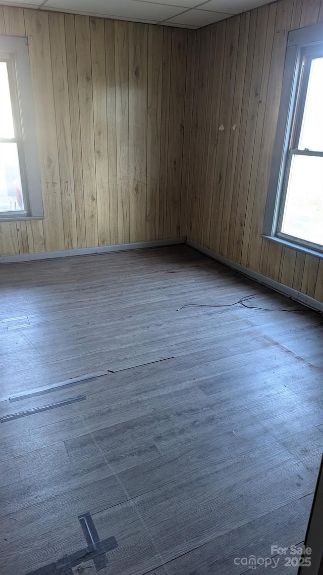 unfurnished room with wooden walls, baseboards, and wood finished floors