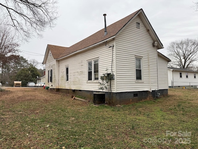 back of property with crawl space, a yard, central AC unit, and a shingled roof