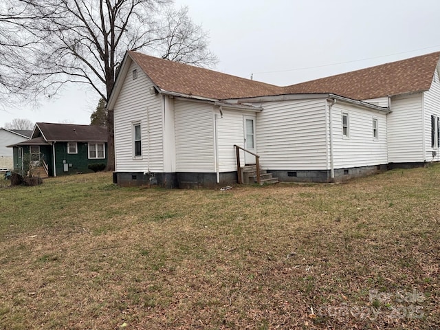 rear view of property featuring entry steps, a lawn, and crawl space