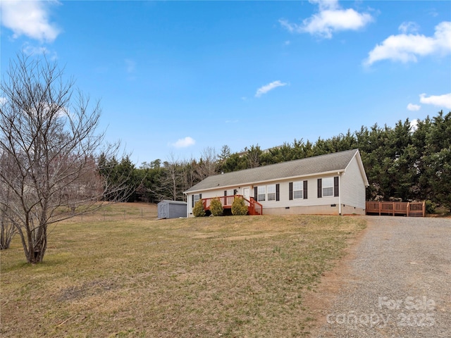 ranch-style home featuring a front yard, a wooden deck, an outdoor structure, crawl space, and a storage shed