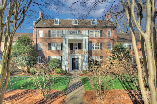 colonial-style house featuring brick siding and a chimney