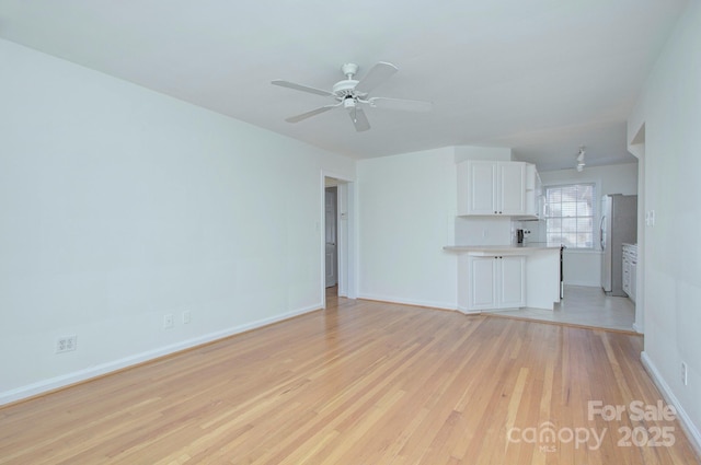 unfurnished living room with a ceiling fan, light wood-type flooring, and baseboards