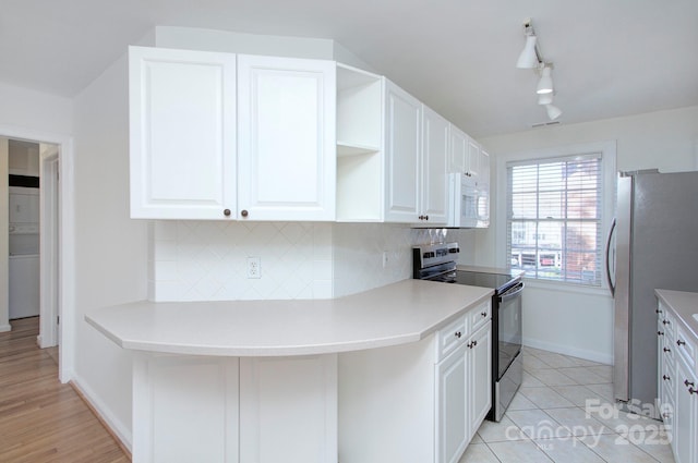 kitchen featuring backsplash, white microwave, freestanding refrigerator, and range with electric stovetop