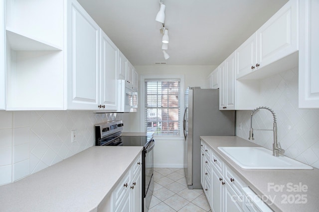 kitchen featuring appliances with stainless steel finishes, white cabinetry, and a sink