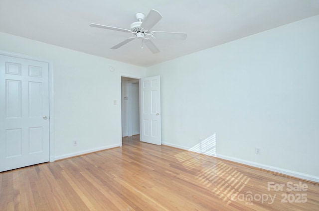 spare room with light wood-style flooring, a ceiling fan, and baseboards