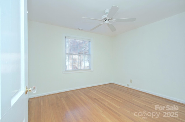 spare room with light wood-type flooring, baseboards, visible vents, and a ceiling fan