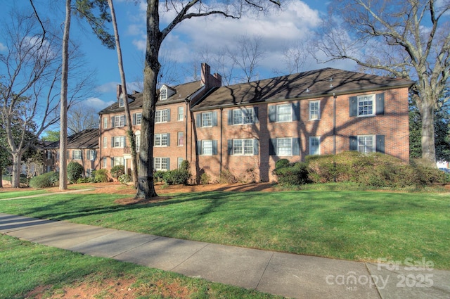 view of front of home with a front lawn, brick siding, and a chimney