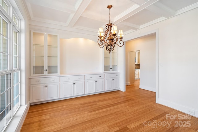 unfurnished dining area with a healthy amount of sunlight, coffered ceiling, light wood-type flooring, and baseboards