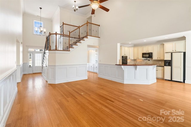 kitchen with dark countertops, black appliances, light wood-style floors, a kitchen bar, and crown molding