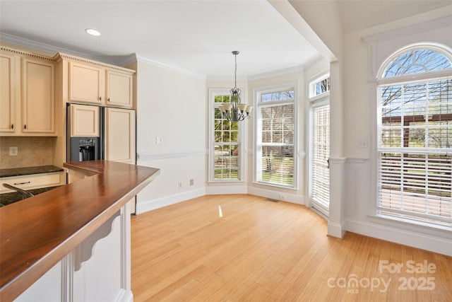 interior space featuring light wood-style flooring, recessed lighting, an inviting chandelier, crown molding, and baseboards