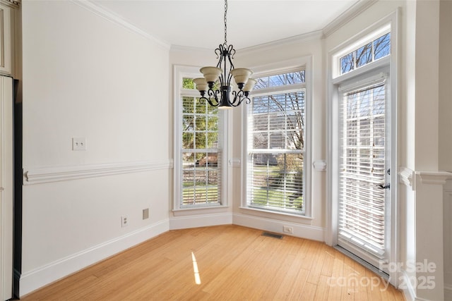 unfurnished dining area with a healthy amount of sunlight, light wood-type flooring, and ornamental molding