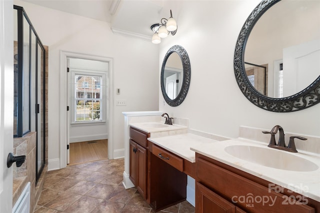 bathroom with a shower stall, double vanity, baseboards, and a sink