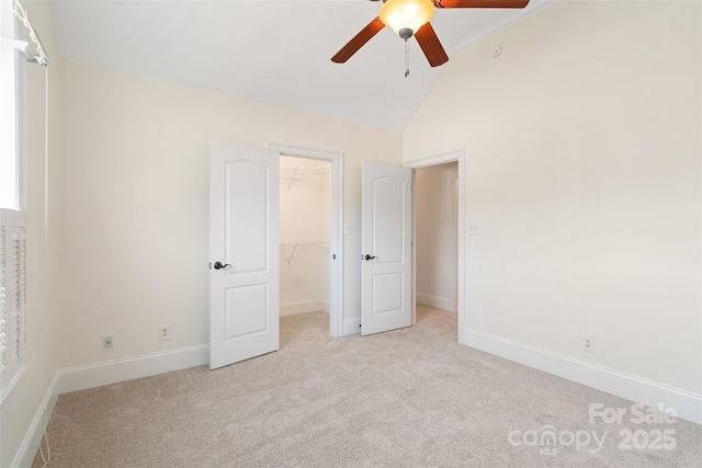 unfurnished bedroom featuring a closet, a walk in closet, baseboards, and carpet floors