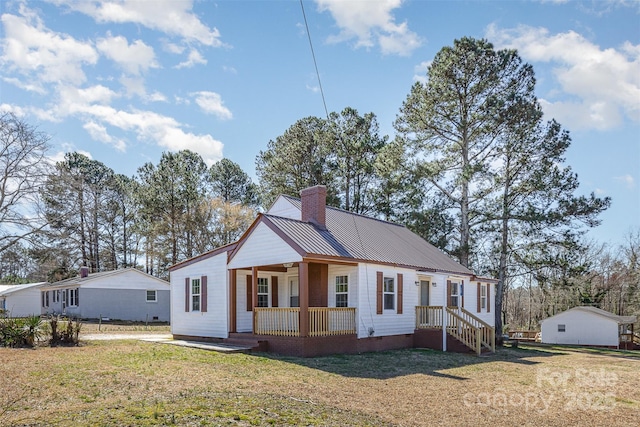 view of front of home featuring a front lawn, a porch, metal roof, crawl space, and a chimney