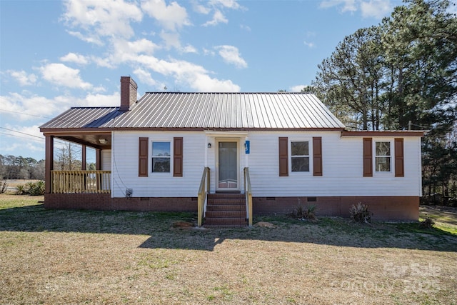 view of front of house with crawl space, a chimney, a front yard, and metal roof