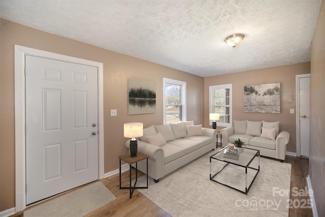 living area with wood finished floors, baseboards, and a textured ceiling