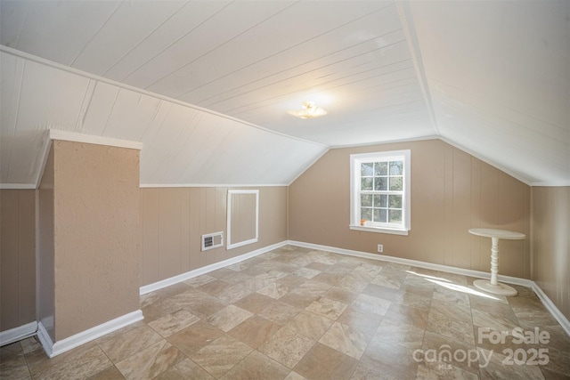 bonus room featuring lofted ceiling, wooden walls, baseboards, and visible vents