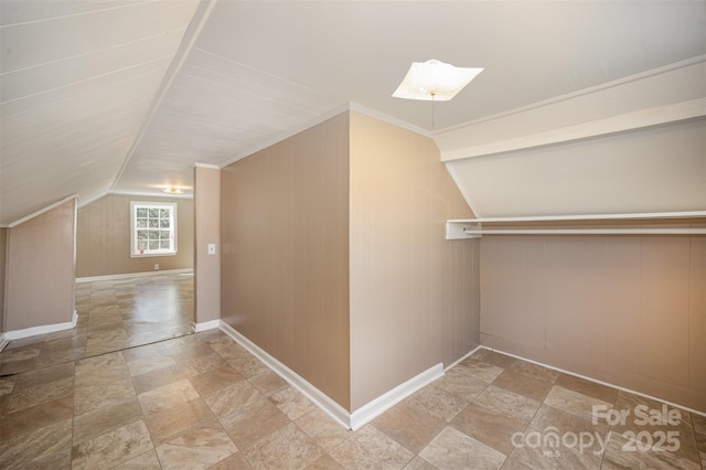 bonus room featuring stone finish flooring, lofted ceiling, baseboards, and wood walls