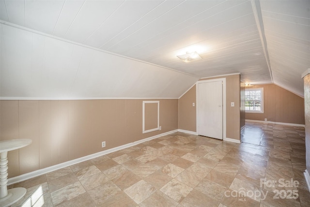 additional living space featuring baseboards and vaulted ceiling