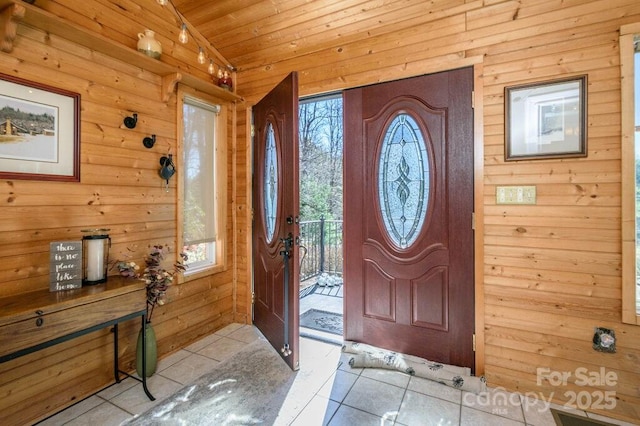 foyer featuring wood ceiling, wooden walls, a healthy amount of sunlight, and light tile patterned floors