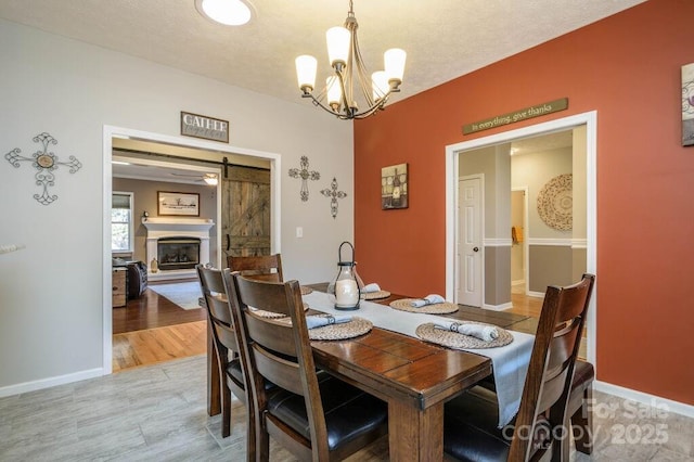 dining area featuring baseboards, a textured ceiling, a chandelier, and light wood finished floors