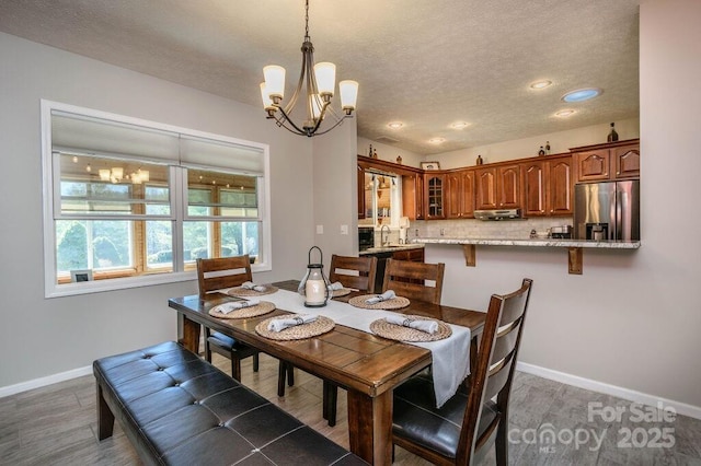 dining space with a notable chandelier, baseboards, and a textured ceiling