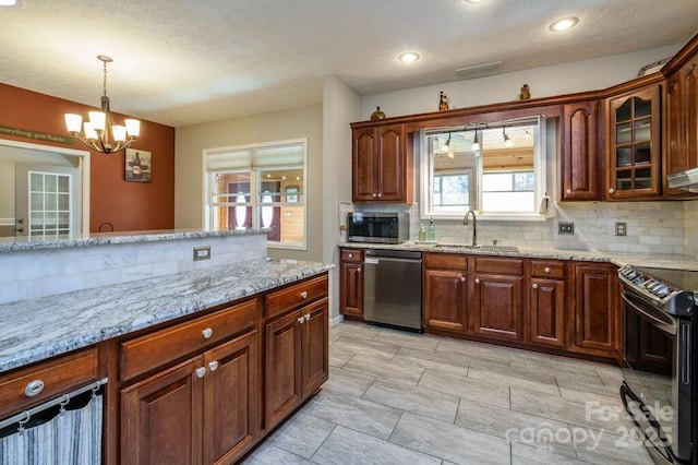 kitchen with a sink, stainless steel appliances, an inviting chandelier, and decorative backsplash