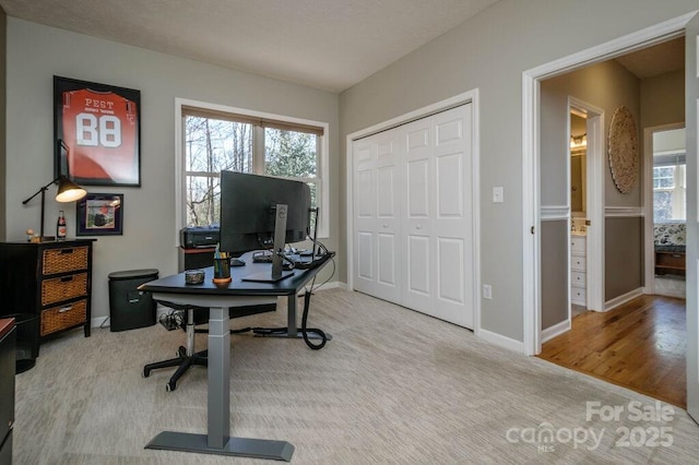 carpeted office space featuring baseboards