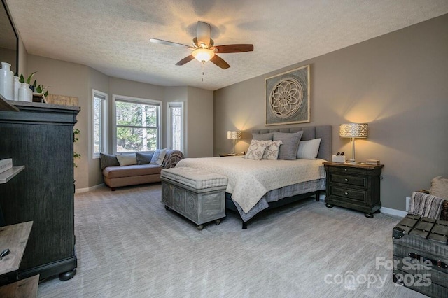 carpeted bedroom featuring ceiling fan, baseboards, and a textured ceiling