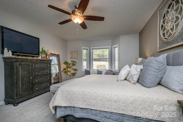 bedroom with light carpet, a textured ceiling, and a ceiling fan