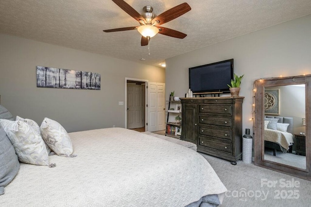 carpeted bedroom featuring ceiling fan and a textured ceiling