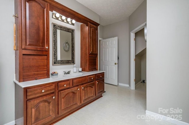 bathroom featuring vanity, baseboards, and a textured ceiling